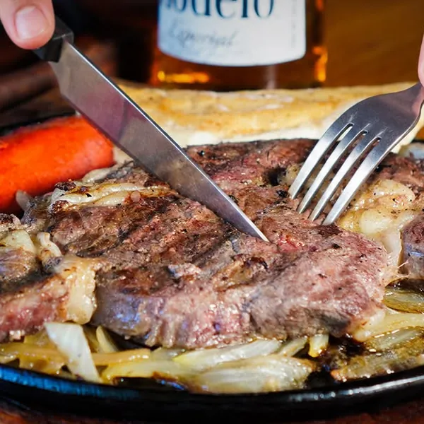 Rib Eye al carbón sobre plancha con cebolla